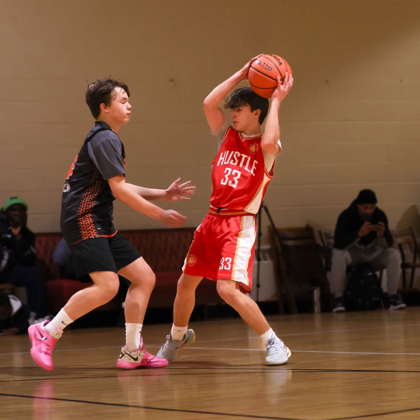 H-Town Hustle player in a red uniform holding a basketball overhead during a game