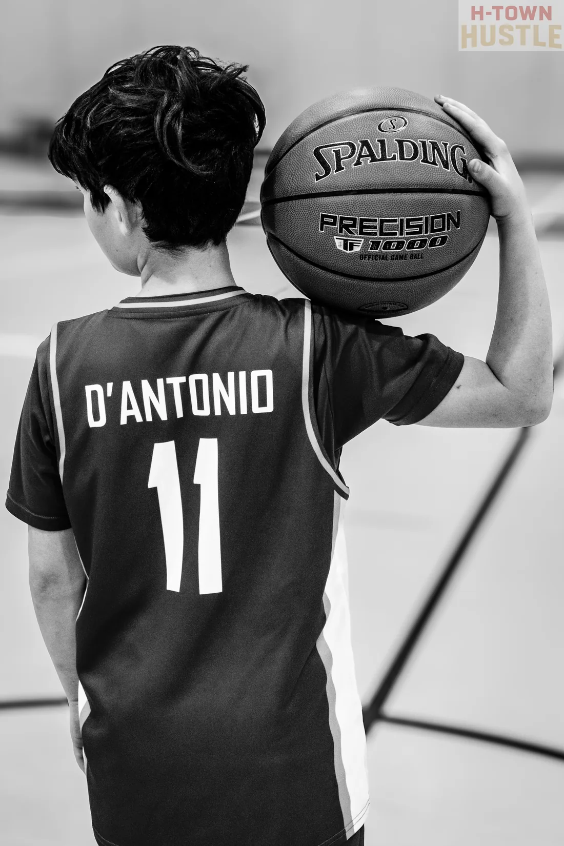 Black and white photograph of a H-Town Hustle player with a basketball on his shoulder